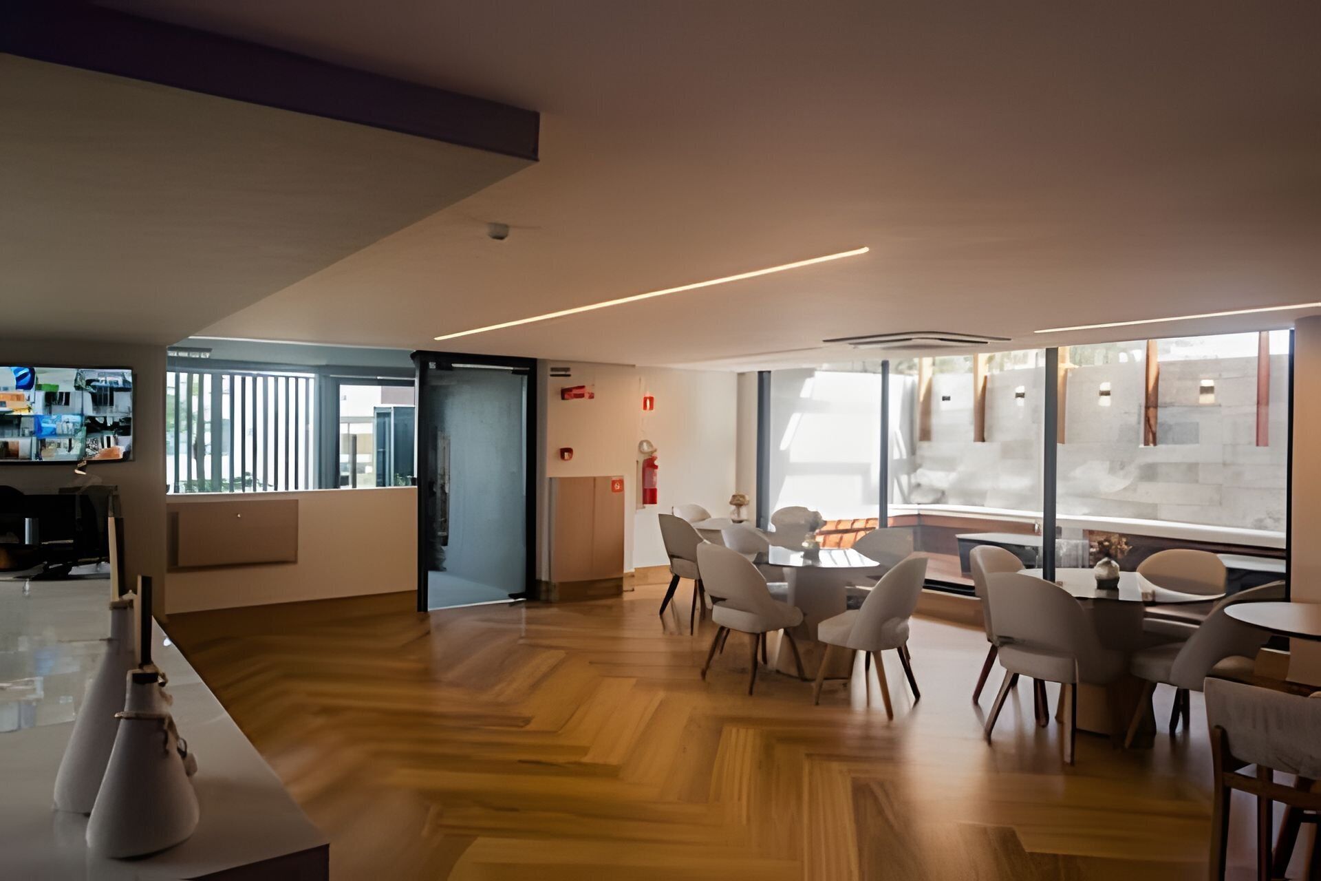 Un intérieur moderne avec un plancher en bois, des chaises blanches et une cloison en verre.