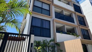 A multi-story building with balconies, a gated entrance, and a pool area. - Ozean (João Pessoa)
