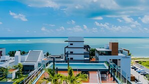 A modern hotel with a rooftop pool, a view of the ocean, and a clear sky. - Ozean (João Pessoa)