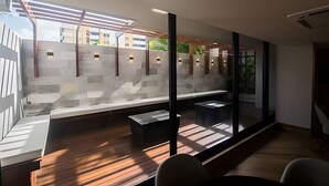 A modern interior with a seating area, a stone wall, and large windows. - Ozean (João Pessoa)
