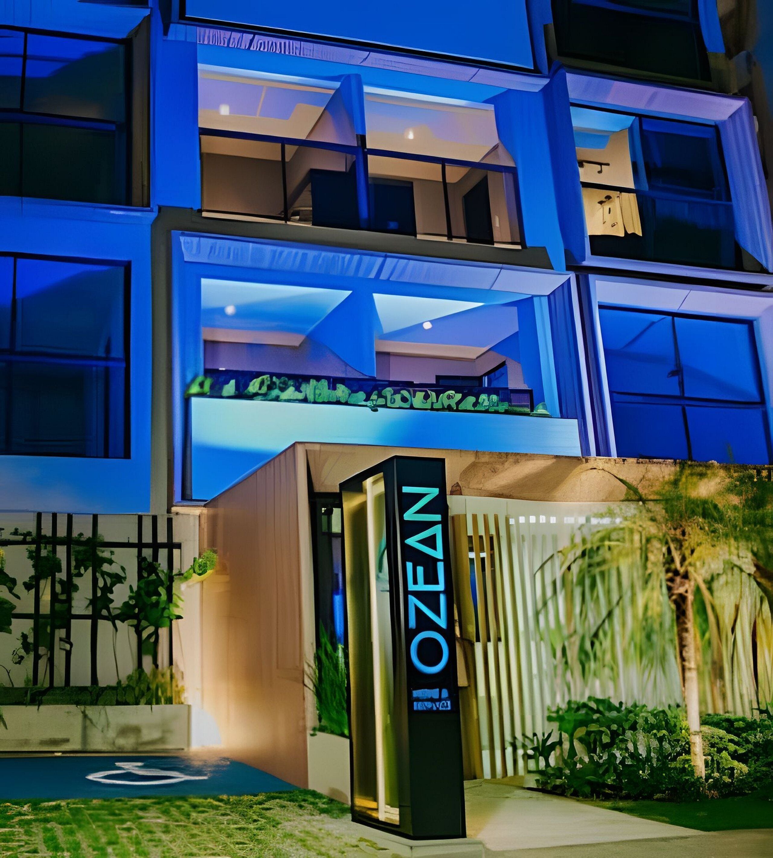 A modern building with a prominent 'OZEAN' sign, large windows, and a rooftop garden.