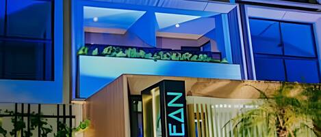 A modern building with a prominent 'OZEAN' sign, large windows, and a rooftop garden.