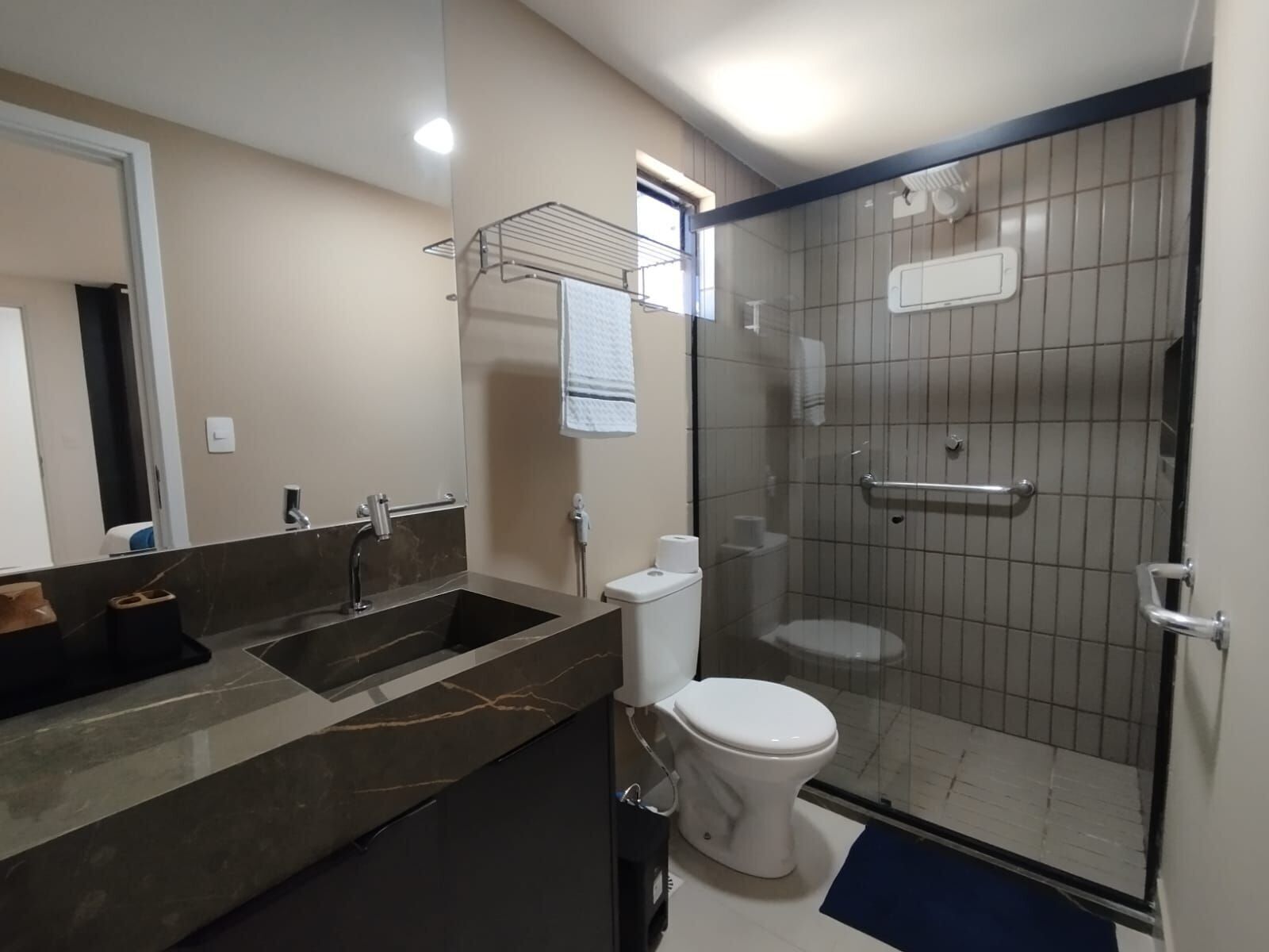 A bathroom with a shower, toilet, sink, and a mirror.
