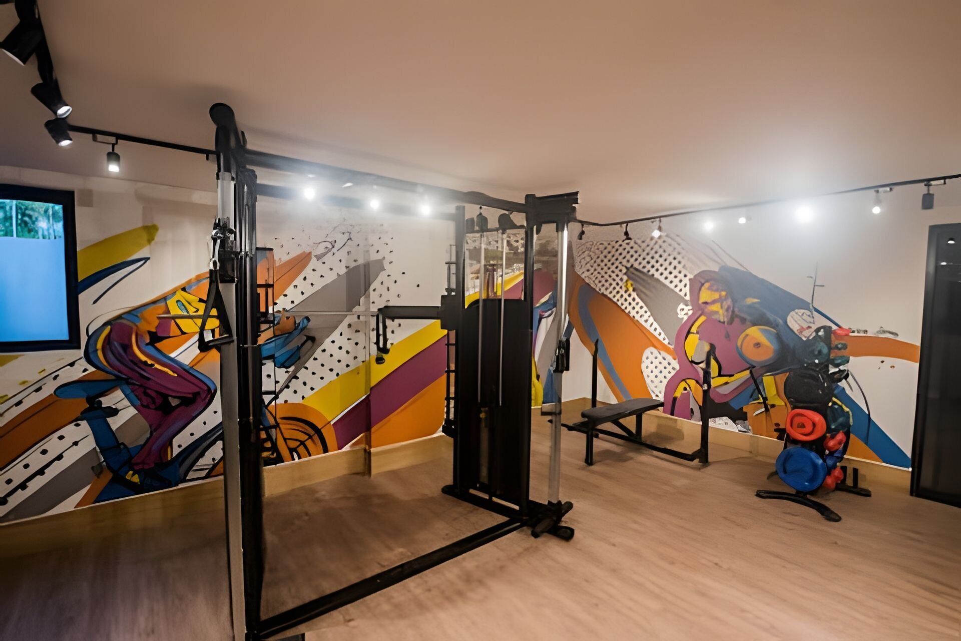 A gym with exercise equipment, a TV, and colorful wall art.
