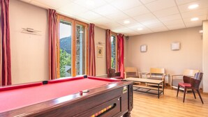 A pool table in a room with a wooden floor, a window with curtains, and a seating area with chairs. - Duplex Chalet With Terrace (Gresse-en-Vercors)