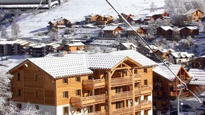 A wooden building with balconies, surrounded by other similar buildings, set in a snowy landscape. - Appartment in Vaujany (Les Deux Alpes)