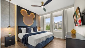 A modern bedroom with a large bed, a ceiling fan, a large window, and a wall-mounted TV. - Last Minute Disney Getaway! Private Pool, Game Room & Themed Bedrooms. Book Now! #173135 (Orlando)