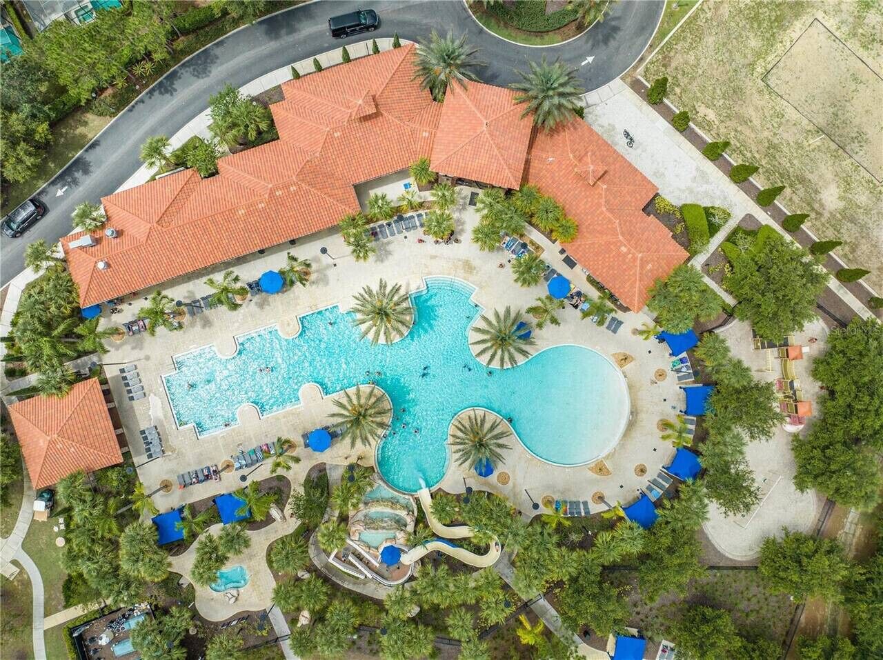 Eine Vogelperspektive zeigt ein Resort mit einem großen zentralen Pool, mehreren kleineren Pools und einer gewundenen Wasserrutsche.