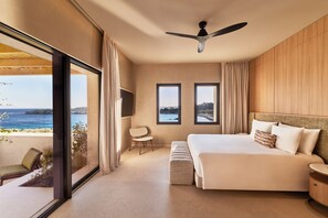 A hotel room with a large bed, a TV, a ceiling fan, and a view of the sea. - Fouquet's Mykonos (Mykonos)