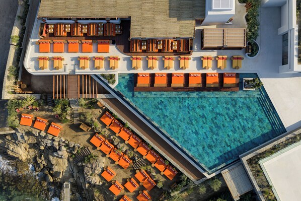 Vista aérea de un complejo turístico con piscina, zonas de estar al aire libre y una zona de comedor.
