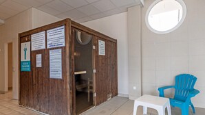 A small wooden structure with signs, a white plastic chair, and a blue chair in a tiled room. - Ocean-view Duplex for 8 (Plougonvelin)