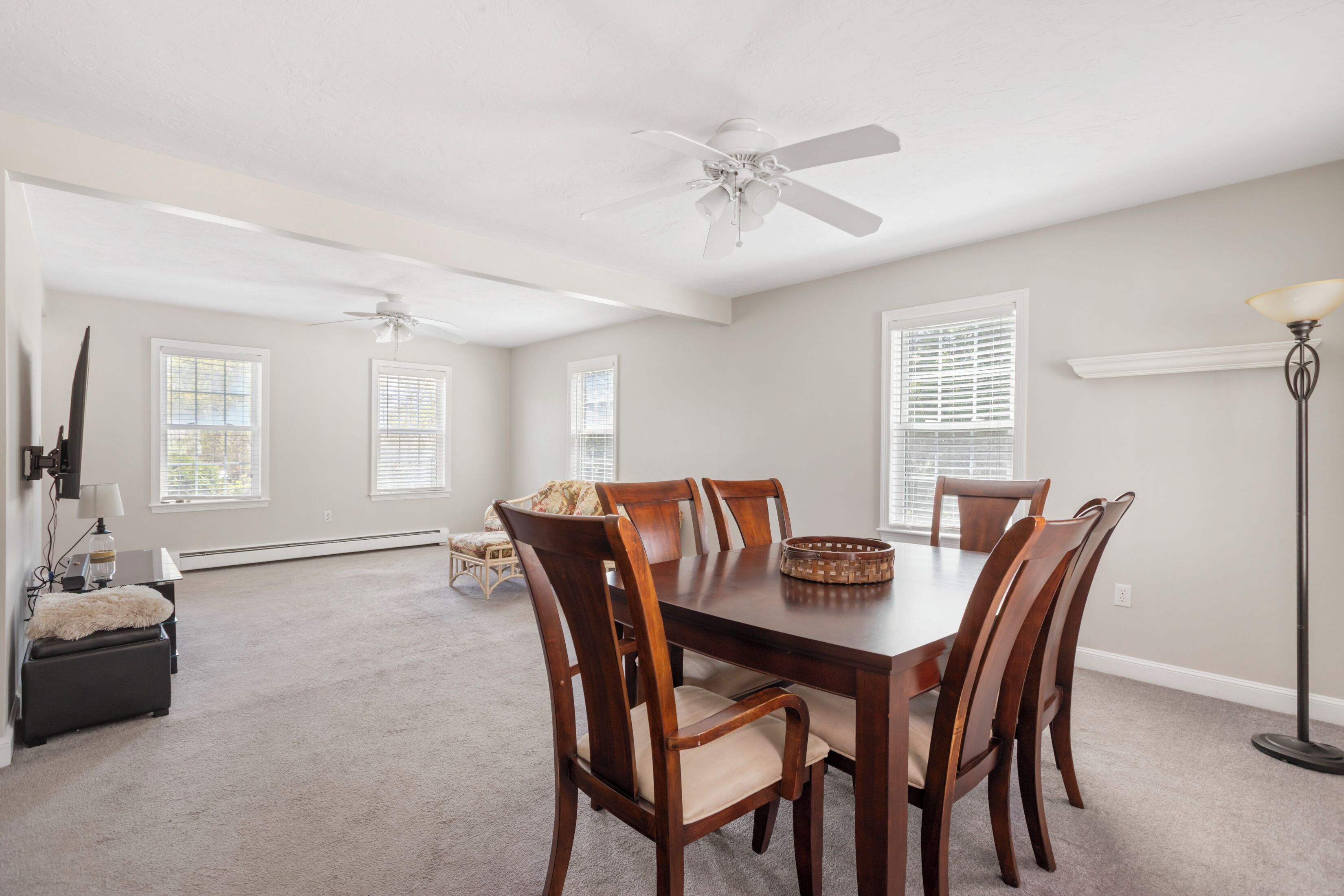 A dining room with a wooden table and chairs, a ceiling fan, and a floor lamp.
