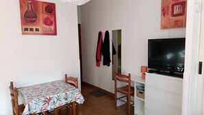 A room with a dining table, chairs, a TV, a white cabinet, and wall art. - Apartment “Sauges 16” with Wi-Fi (Cazaubon)