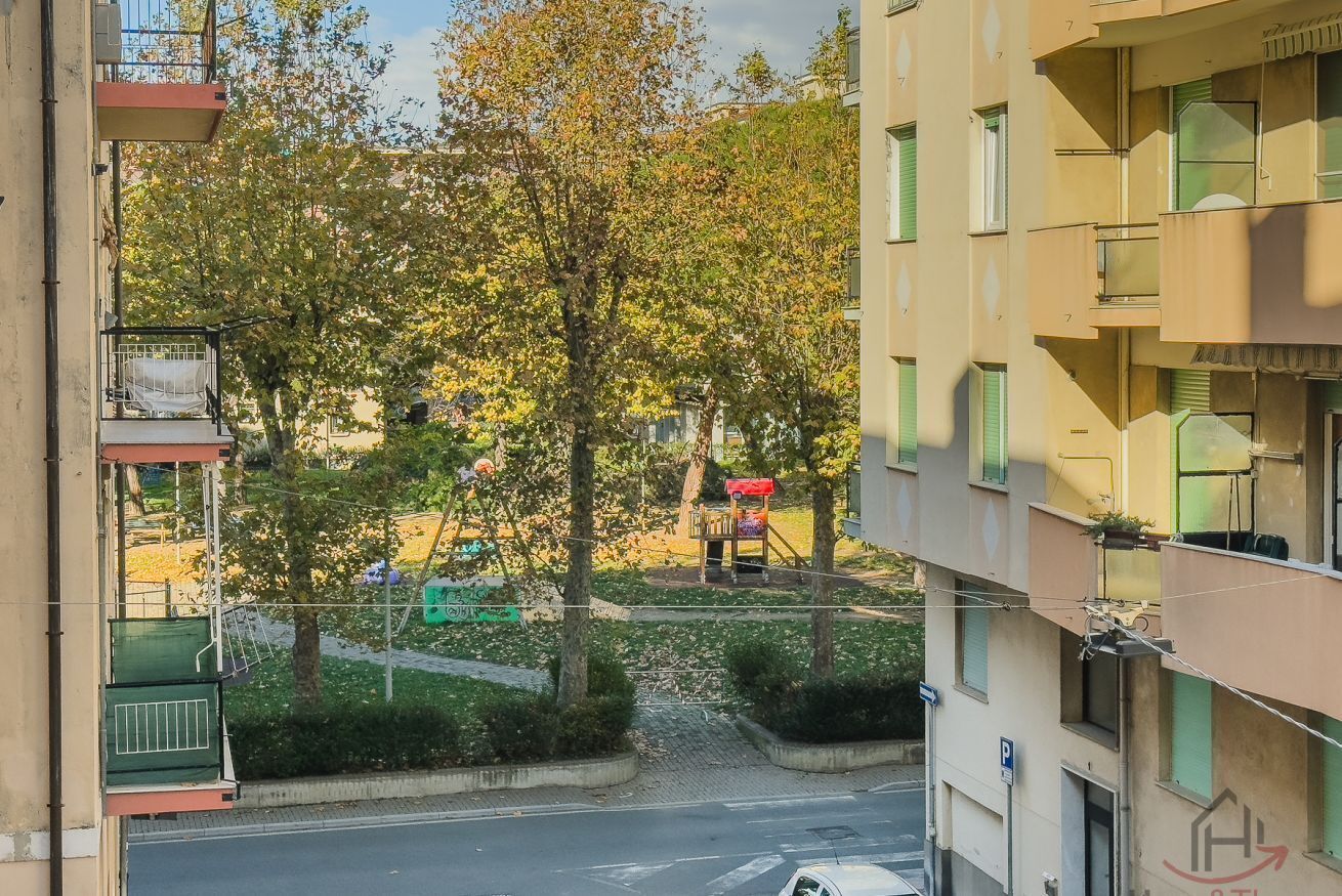 En byggnad med flera våningar, balkonger, en stenlagd innergård och ett träd.