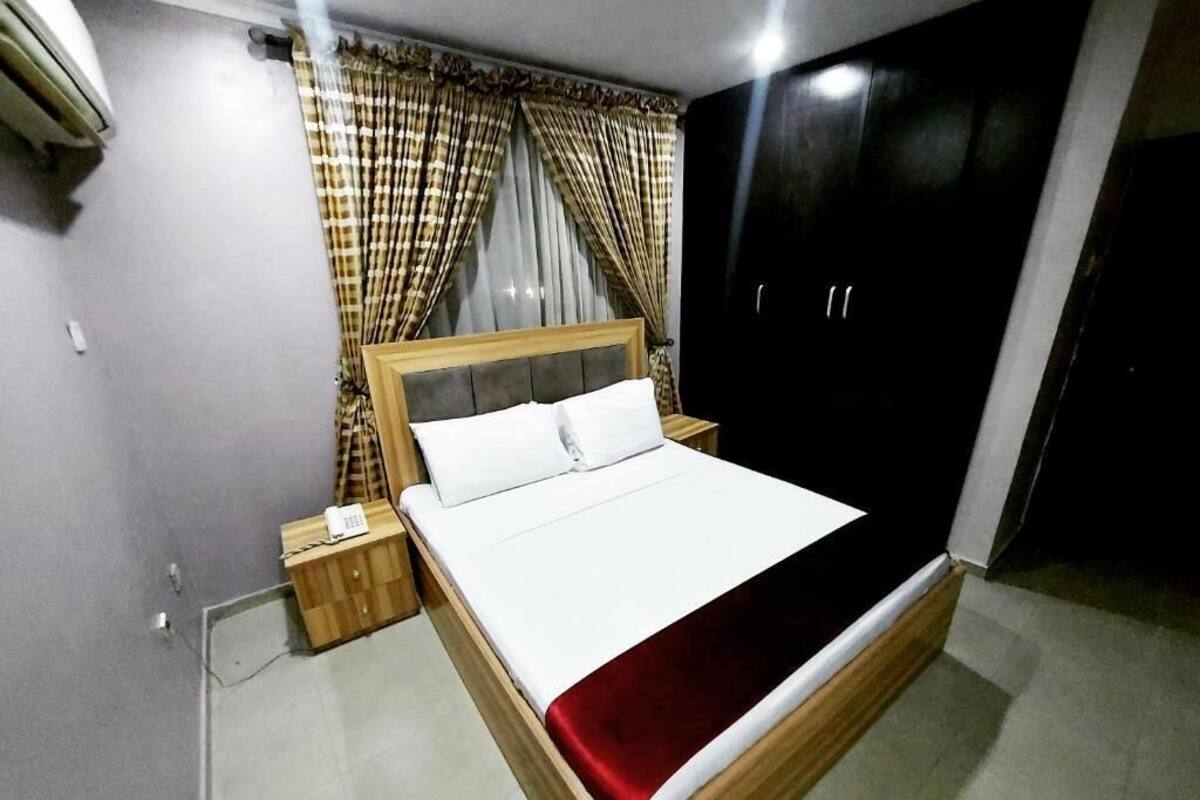 Une chambre à coucher avec un lit, des rideaux, une armoire et une table de chevet.