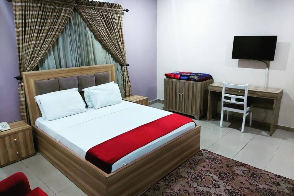 Une chambre à coucher comprenant un lit, un bureau, une chaise, une télévision et une armoire.