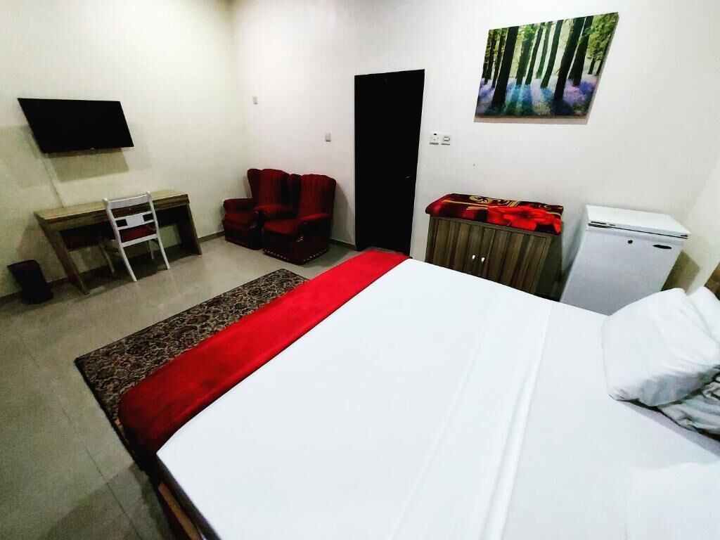 Une chambre à coucher comprenant un lit, un bureau, une chaise, un téléviseur, une armoire et une porte.