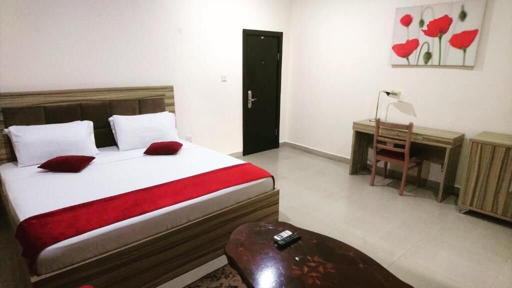 A bedroom with a bed, a desk, a chair, and a door.