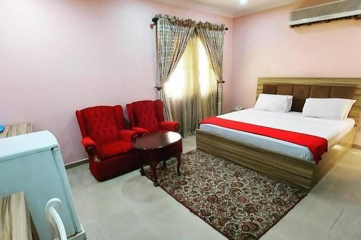 Une chambre d’hôtel avec un lit, un bureau, une chaise et un canapé rouge.