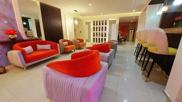 Un moderno vestíbulo de hotel con una zona de estar, una sala de comedor y una recepción.