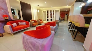 Un moderno vestíbulo de hotel con una zona de estar, una sala de comedor y una recepción.