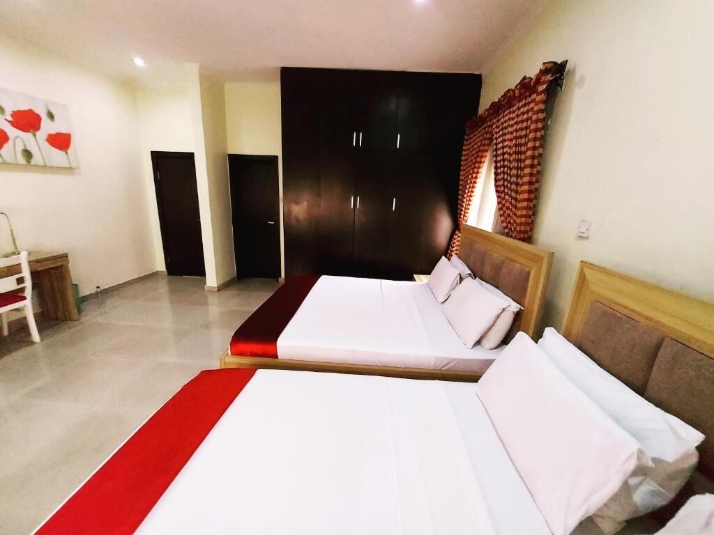 Una habitación de hotel con dos camas, un armario, una silla y un cuadro en la pared.