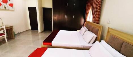 Una habitación de hotel con dos camas, un armario, una silla y un cuadro en la pared.