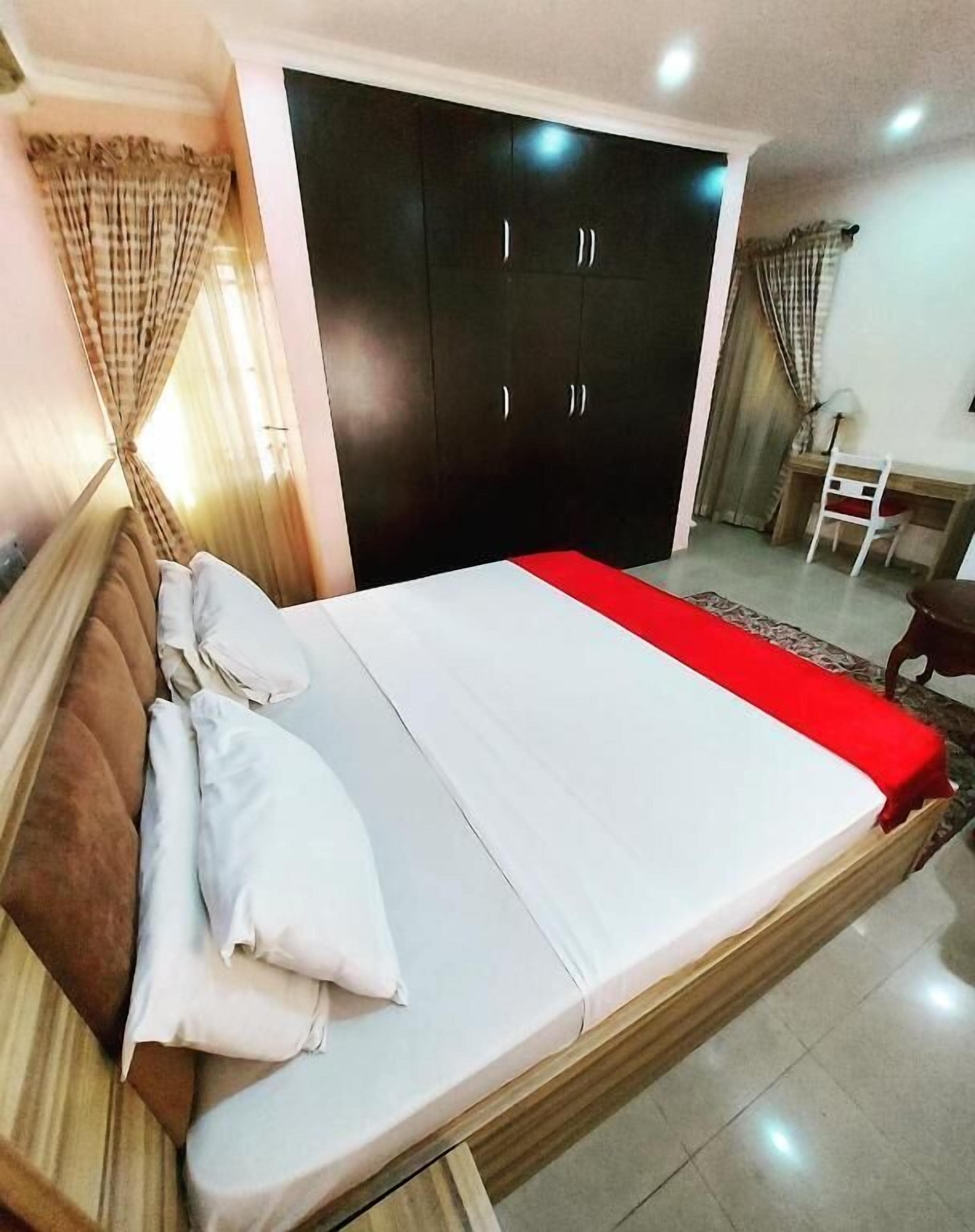 Un dormitorio con cama, armario, escritorio y silla.