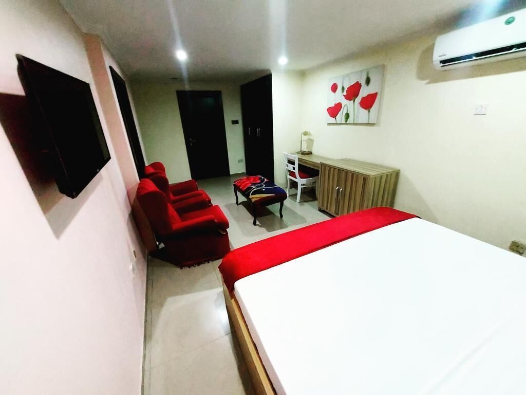 A hotel room with a bed, a desk, a chair, and a TV.
