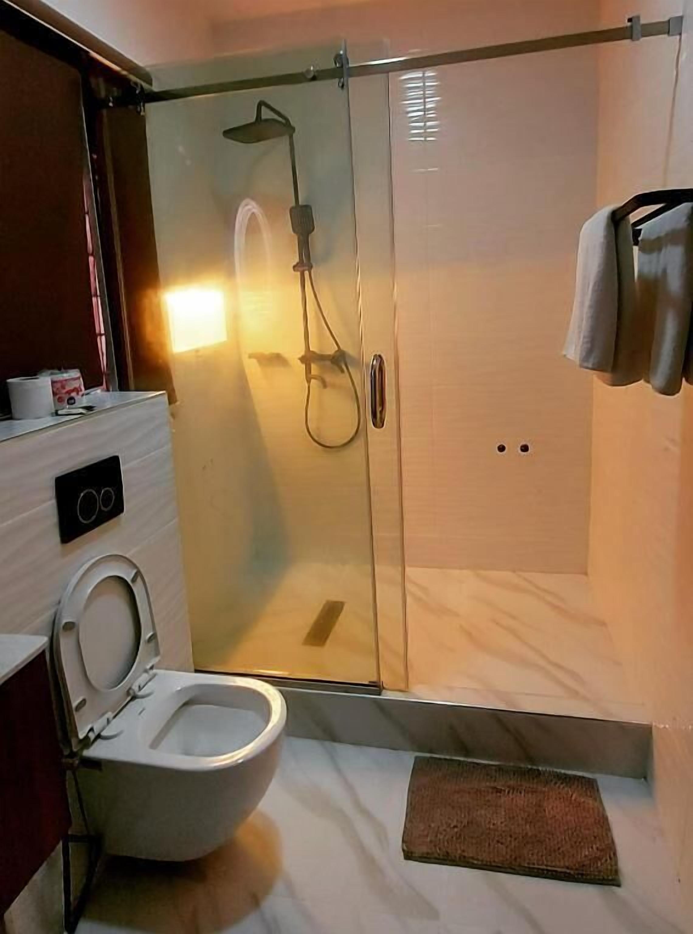 Un baño moderno con ducha de vidrio, inodoro y perchero para toallas.