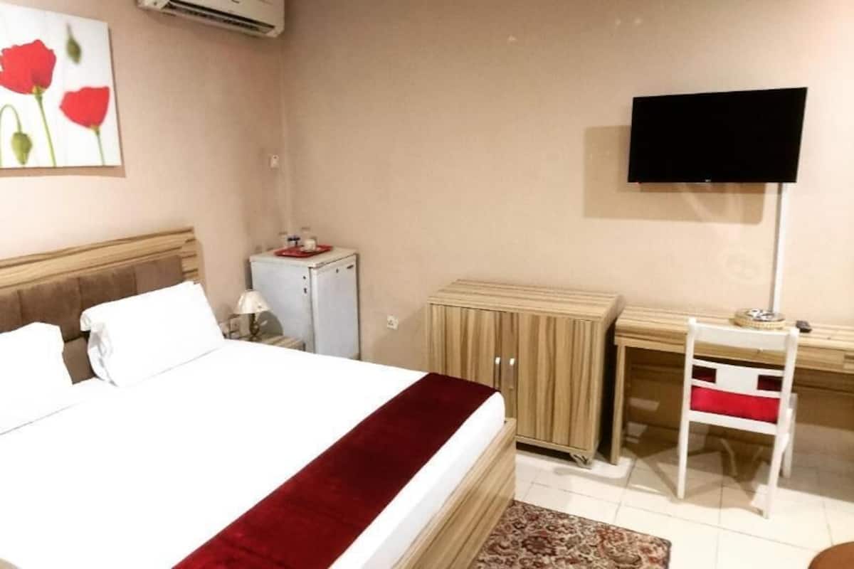 Une chambre d’hôtel équipée d’un lit, d’un bureau, d’une télévision et d’un réfrigérateur.