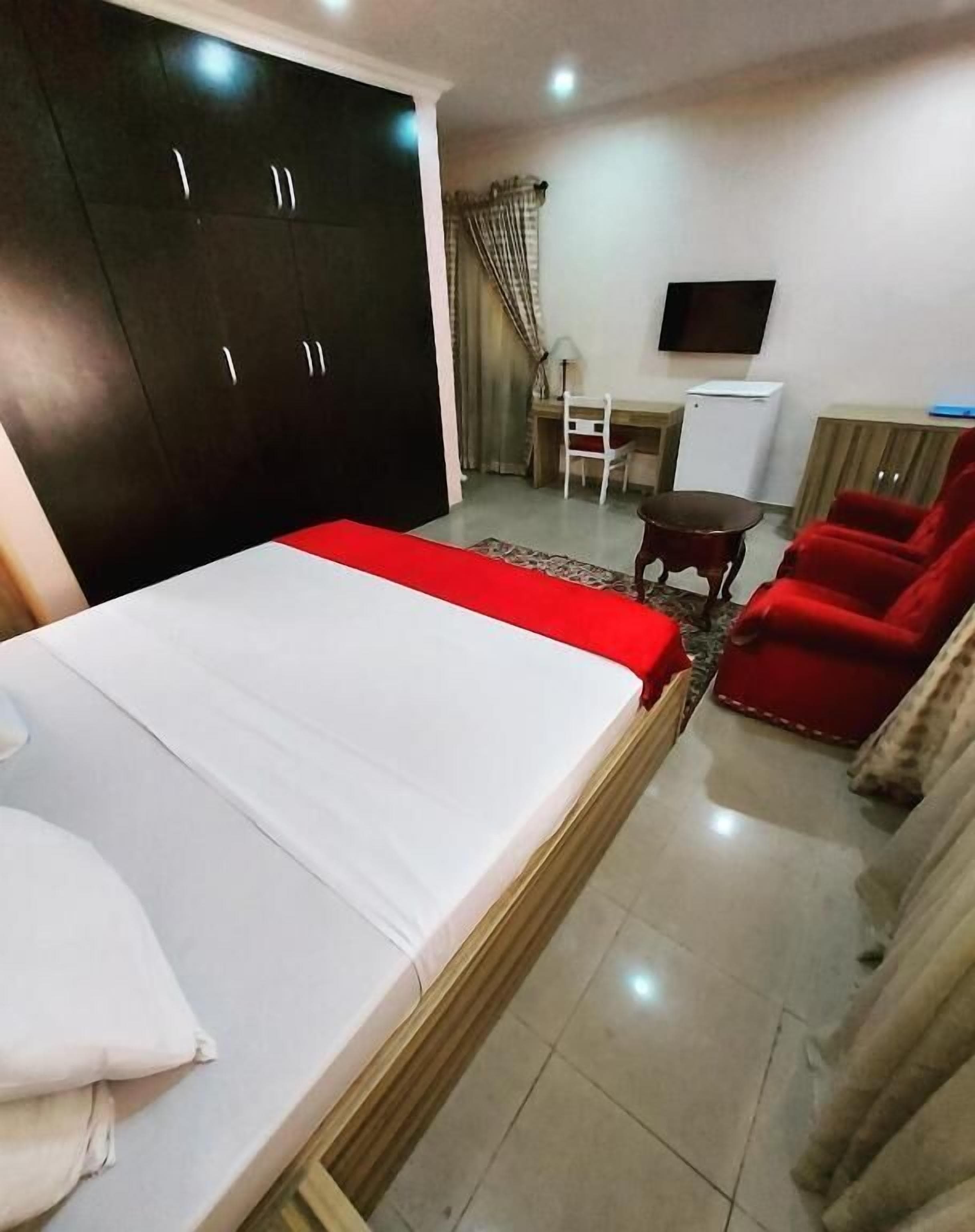 A bedroom with a bed, a desk, a chair, a TV, and a wardrobe.