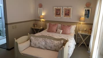 A bedroom with a bed, bedside tables, lamps, a mirror, and two framed pictures on the wall.