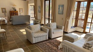 Un salon avec des canapés à rayures, un tapis à motifs et de grandes fenêtres avec des rideaux.