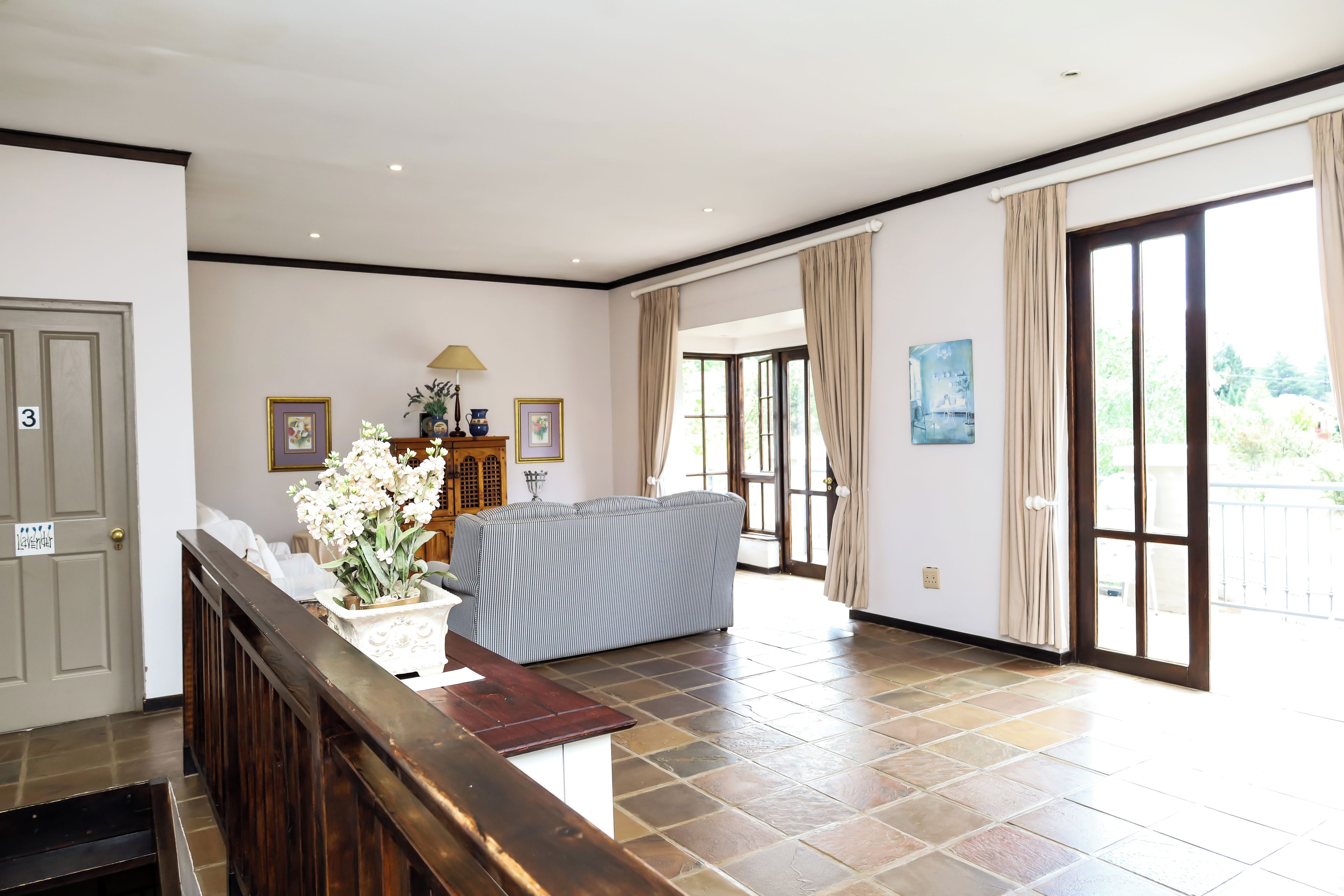 A spacious living area with a sofa, a wooden cabinet, and a large window.