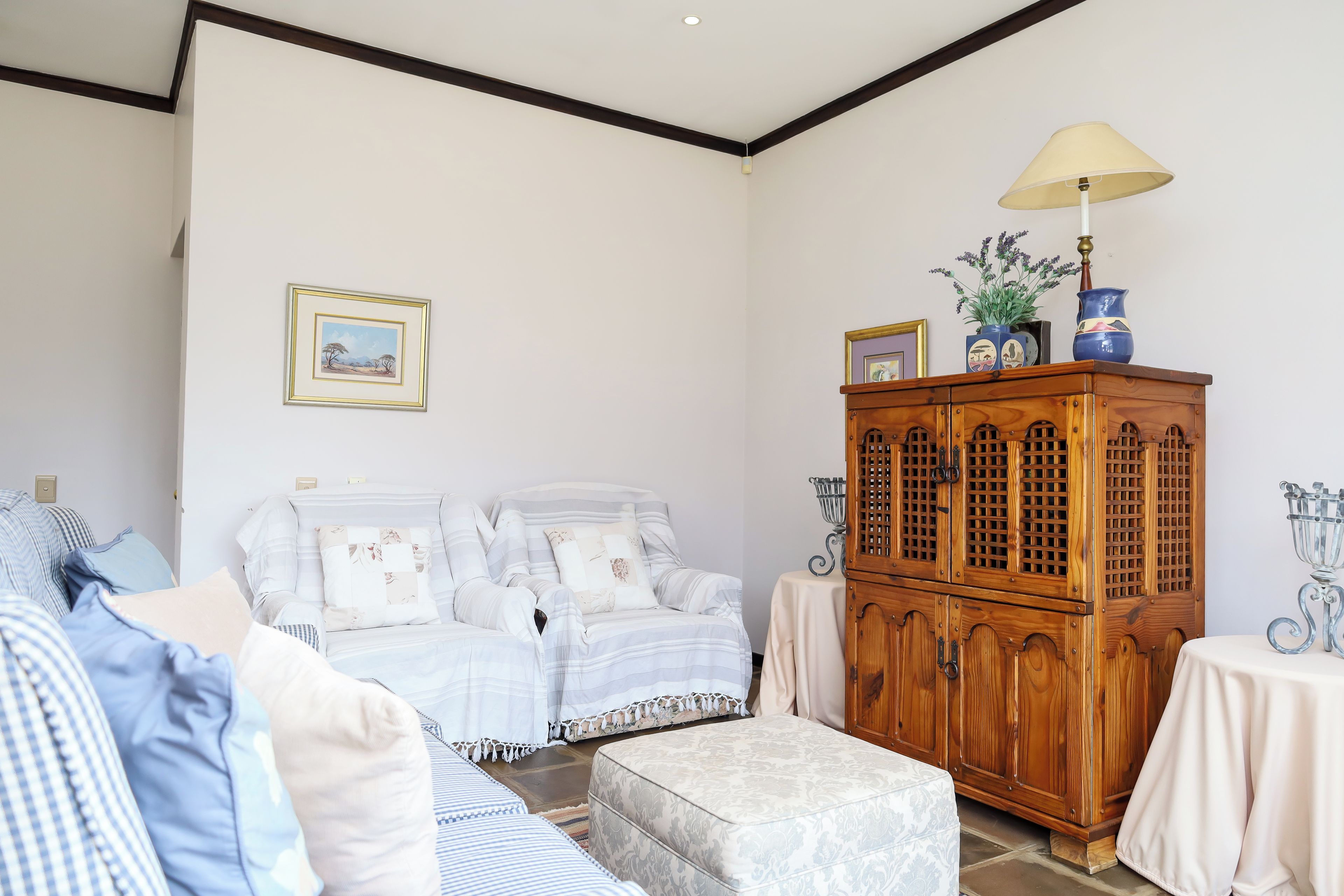 A room with a sofa set, a wooden cabinet, and a lamp.