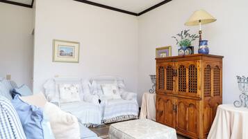 A room with a sofa set, a wooden cabinet, and a lamp.