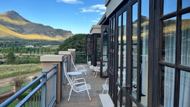 Un balcon avec coin salon extérieur, de grandes fenêtres et une vue sur les montagnes.