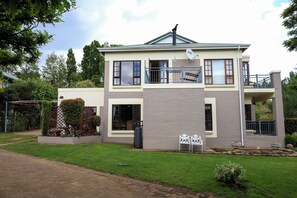 A two-story house with a balcony, a satellite dish, and a well-maintained lawn.