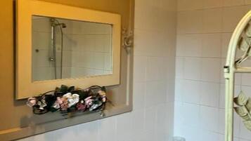 Een badkamer met een bad, een douche, een spiegel en een handdoekhouder.