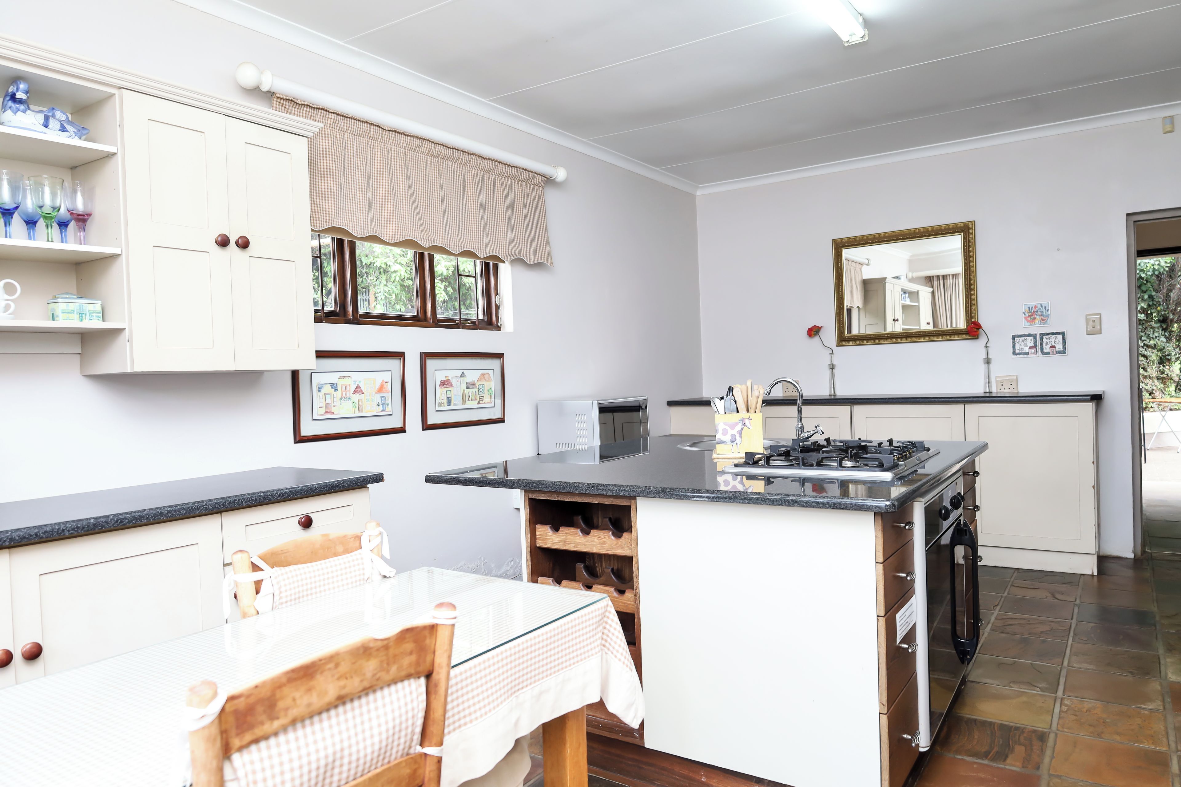 A kitchen with a central island, a dining table, and a window with curtains.
