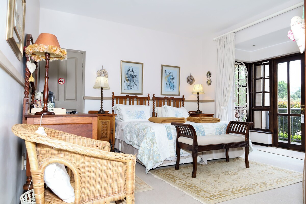 A hotel room with a bed, two bedside tables, a chair, a desk, and a window with a view.
