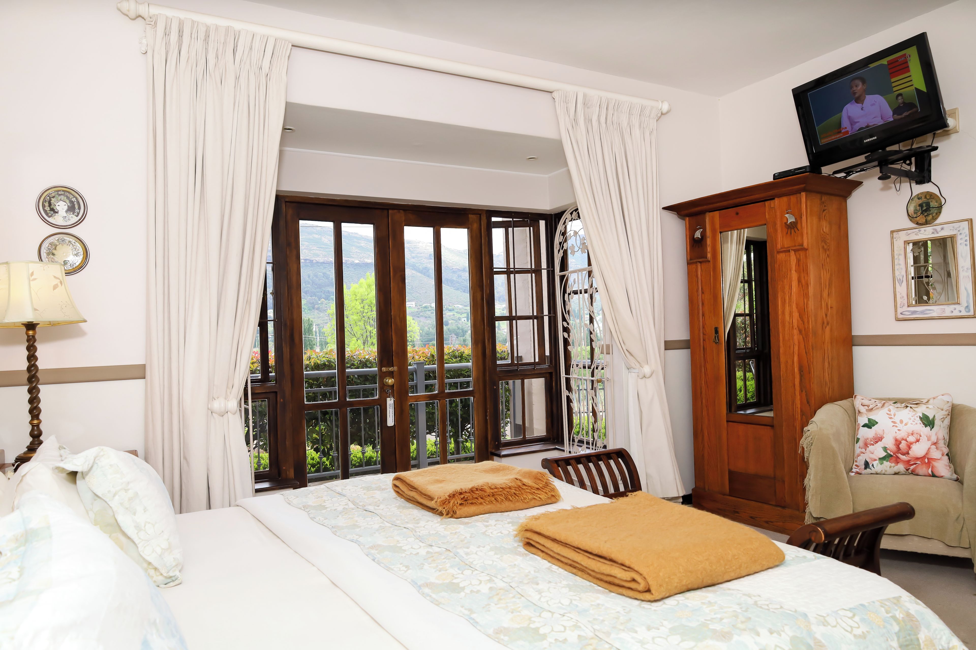 Une chambre d’hôtel avec un lit, une télévision, une armoire en bois et une vue sur la verdure par la fenêtre.