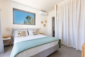 Ein Schlafzimmer mit Bett, Fenster, Klimaanlage, Nachttisch und Tür.