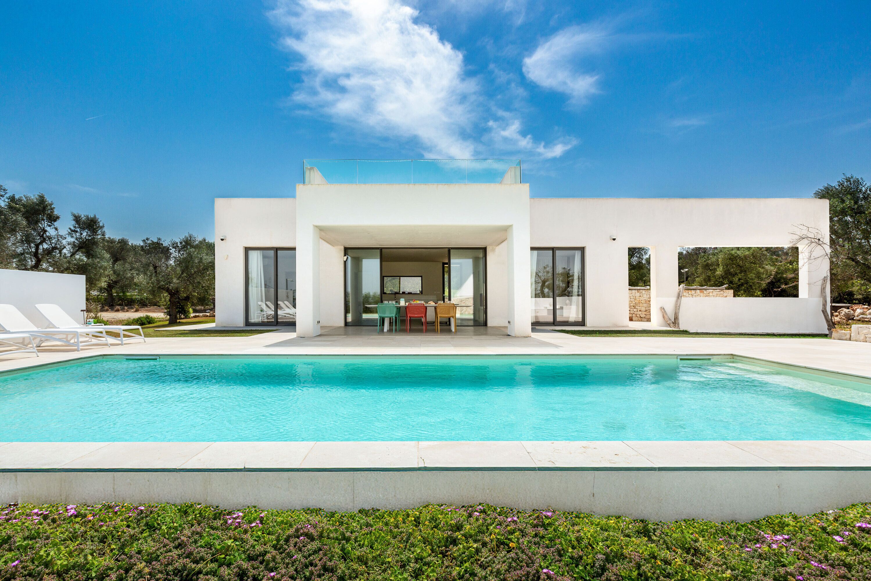 Una casa moderna con piscina, un patio cubierto y vistas del paisaje circundante.
