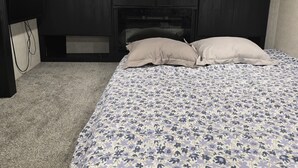A bedroom with a bed, a headboard, a dresser, and a carpeted floor.