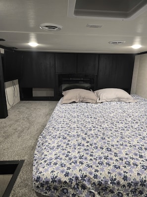 Un dormitorio con cama, cabecera, cómoda y piso alfombrado.