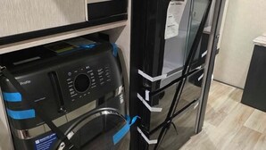 A compact kitchen with a built-in washer and dryer, a refrigerator, and a microwave.