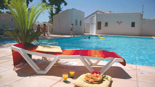 Ein Poolbereich mit Liegestühlen, einem Tisch mit Obst und Getränken und einem klaren, blauen Pool.