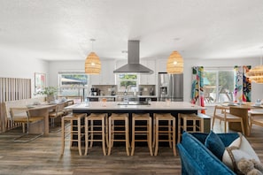 A modern kitchen with a central island, bar stools, and pendant lighting. - Fun & Sun! Heated Pool, Pickleball, Mini Golf, Game Room + More! Sleeps 18! (Seminole)